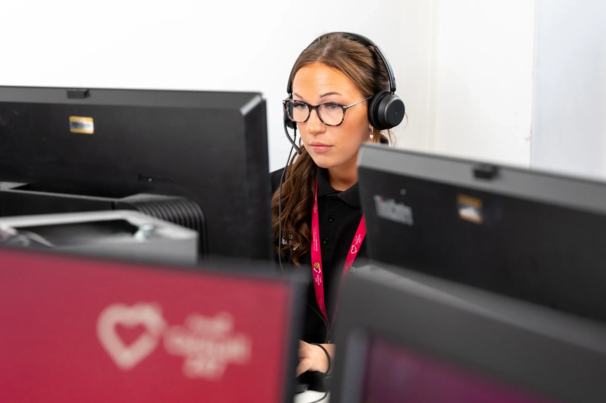 A Provide Carecall247 monitoring centre operator wearing a headset, focused at her workstation.